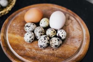 Ovos de codorna e galinha em um prato de madeira foto