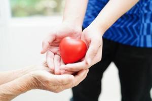 ásia jovem Garoto dar vermelho coração para velho avó com amor e Cuidado. foto