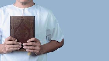 muçulmano homem segurando piedosos livro do Alcorão, isolado em branco fundo foto