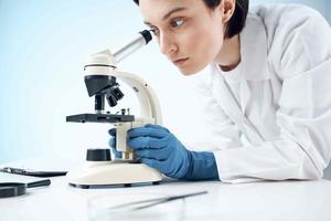 mulher dentro branco casaco parece através microscópio laboratório Ciência profissionais experimentar foto