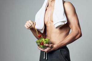 desportivo homem com muscular tronco prato do salada em saudável Comida exercite-se foto