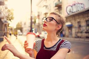 bonita mulher ao ar livre vestindo óculos vidro com beber andar foto