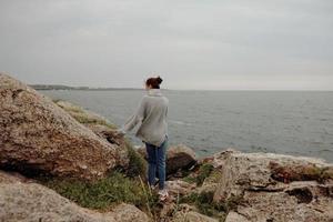 bonita mulher natureza pedras costa panorama oceano relaxamento conceito foto