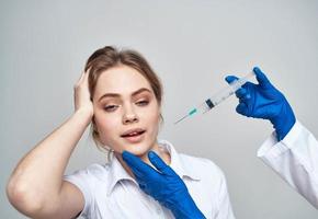 assustado paciente e seringa dentro mão azul luvas remédio foto