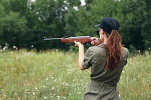 mulher arma visando Caçando alvo traseiro Visão armas verde árvores foto