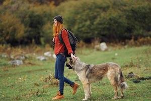 mulher caminhante com uma mochila dentro natureza com uma cachorro foto