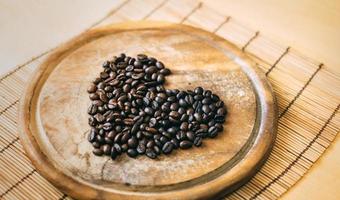 grãos de café em uma placa de madeira em forma de coração foto