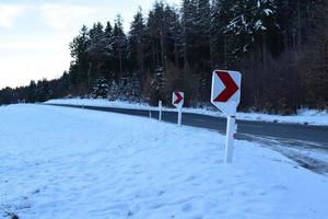 estrada curva com neve e avisar sinais foto
