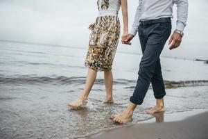 casal caminhando descalço em uma praia foto