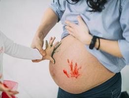 criança pintando a barriga da mãe grávida foto