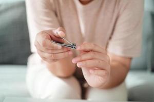 mulher corte unhas usando unha máquina de cortar cabelo, assistência médica, beleza conceito. foto