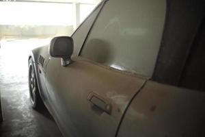 a cheio do poeira coberto em a velho carro abandonado dentro a estacionamento muito. foto