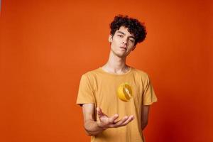 alegre cara com encaracolado cabelo e segurando a laranja isolado fundo foto