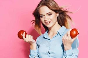 fofa Loiras menina com tomates dentro dela mãos saudável Comida Rosa fundo foto