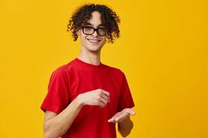 engraçado fofa míope jovem aluna homem dentro vermelho camiseta óculos posando isolado em sobre amarelo estúdio fundo. a melhor oferta com livre Lugar, colocar para anúncio. Educação Faculdade conceito foto