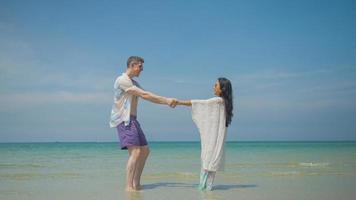 casais aguarde mãos e andar ao longo a de praia em seus verão período de férias e elas sorrir e ter Diversão em período de férias. foto