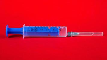seringa médica azul em um close up de fundo vermelho