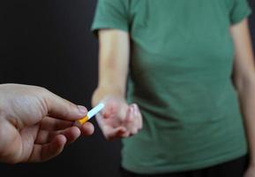 cara dando um cigarro para a garota em um fundo escuro foto