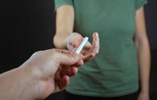 cara dando um cigarro para a garota em um fundo escuro foto