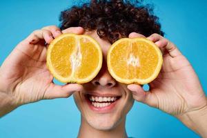 alegre encaracolado cara com laranjas dentro dele mãos frutas estilo de vida foto