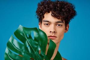 bonito homem com encaracolado cabelo nu ombros verde folha Claro pele foto