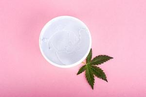 cosméticos de maconha, creme natural de maconha e folha verde em fundo rosa foto