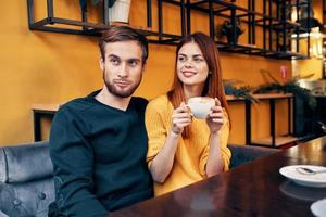 bonito homem dentro suéter e mulher com uma copo do café encontro amor restaurante cafeteria foto
