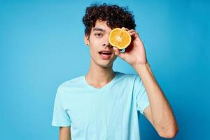 cara com encaracolado cabelo segurando a laranja fruta azul fundo foto