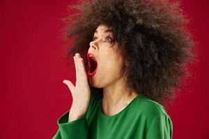 bonita jovem fêmea afro Penteado verde vestir emoções fechar-se vermelho fundo inalterado foto