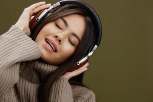 jovem mulher dentro uma suéter ouvindo para música com fones de ouvido Diversão verde fundo foto