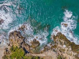 aéreo Visão do mar falhando ondas branco espuma ondas em Beira Mar pedras topo Visão foto