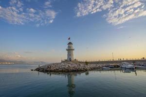 uma Maravilhoso farol às pôr do sol em a Mediterrâneo costa foto