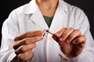 médico de jaleco branco quebra um cigarro foto