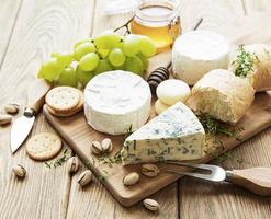 seleção de queijo, mel e uva em um velho fundo de madeira foto