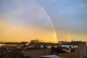 panorama com pôr do sol em uma arco Iris sobre a telhados do casas dentro uma espanhol Cidade foto