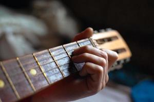 dedos seguram o acorde e guitarra acústica foto