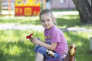 lindo seis ano velho menina tocam dentro a jardim. foto