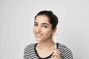 alegre mulher dentro uma listrado camiseta escova de dente dentro mão isolado fundo foto