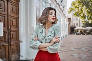 fofa Loiras menina com vermelho lábios ao ar livre andar perto a construção foto