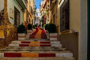 Antiguidade Escadaria dentro calpe, Espanha dentro a velho Cidade pintado vermelho e amarelo dentro a cor do a do país bandeira foto