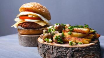 Batatas fritas com cogumelos e um suculento hambúrguer em tábuas de madeira da floresta