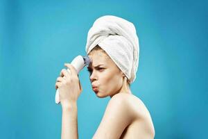 alegre mulher com uma toalha em dela cabeça massageadores dentro mãos dermatologia limpar \ limpo pele foto