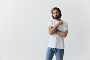 retrato do uma homem com uma Preto Grosso barba e grandes cabelo dentro uma branco camiseta em uma branco isolado fundo emoção do tristeza e anseio foto