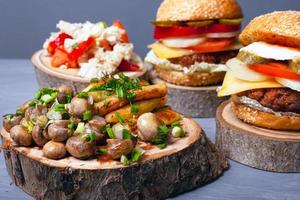 batatas fritas com cogumelos e suculentos hambúrgueres de carne em tocos de madeira