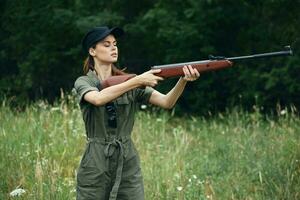 mulher em ao ar livre segurando uma arma dentro frente do ele Caçando lado Visualizações verde folhas verde foto