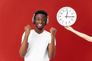 homem do africano aparência dentro fones de ouvido Próximo para relógio dentro branco camiseta foto