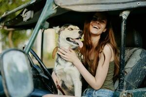 mulher e rouco cachorro alegremente viajando dentro carro sorrir com dentes outono andar com bicho de estimação, viagem com cachorro amigo abraços e danças foto