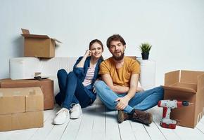 uma homem e uma mulher com caixas estão em movimento. bem, a apartamento é ser renovado de uma família foto