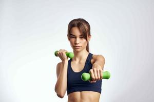 esportivo mulher com halteres dentro mãos bombeado acima pressione ginástica exercício Academia foto