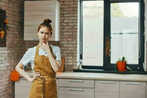 uma dona de casa dentro a avental gestos com dele mãos dentro a cozinha tarefas domésticas casa vida foto